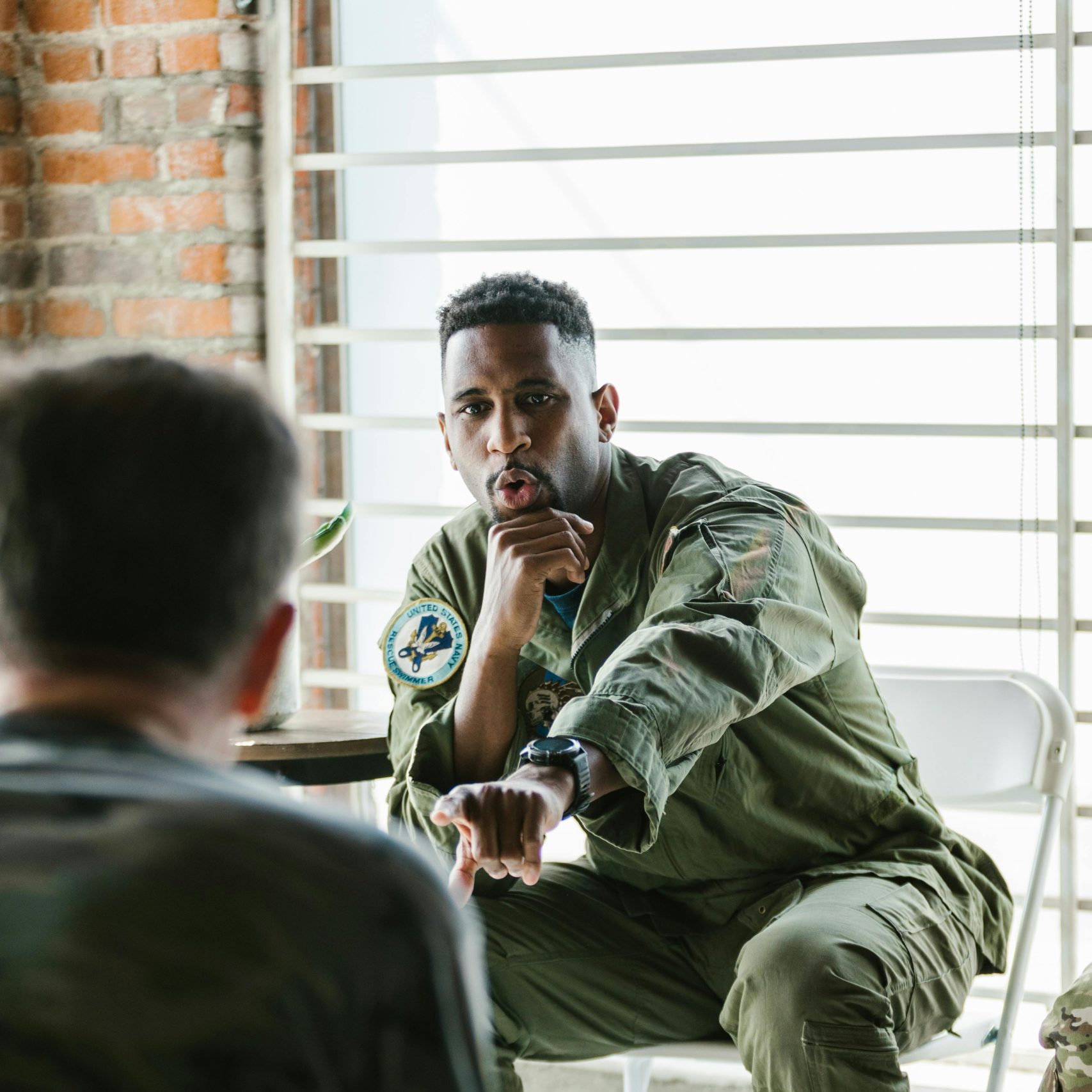African American military officer in debriefing session with soldiers indoors.